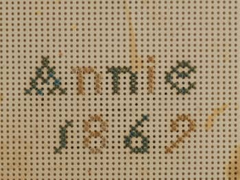 Detail of embroidery sampler, showing the perforated cardboard used to make the sampler.