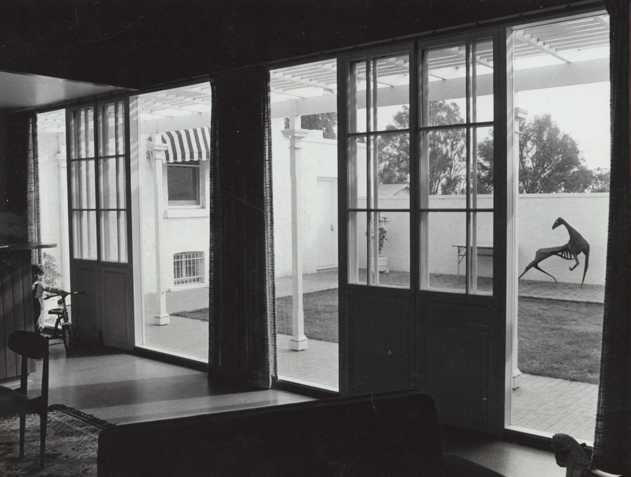 External photograph of the former Fulham Park Stud homestead on Fulham Park Drive, Lockleys, after alteration work designed by John S. Chappel Pty Ltd, architect. View from inside looking out to the walled garden through open wooden sliding doors. SLSA: BRG 346/29/1/6