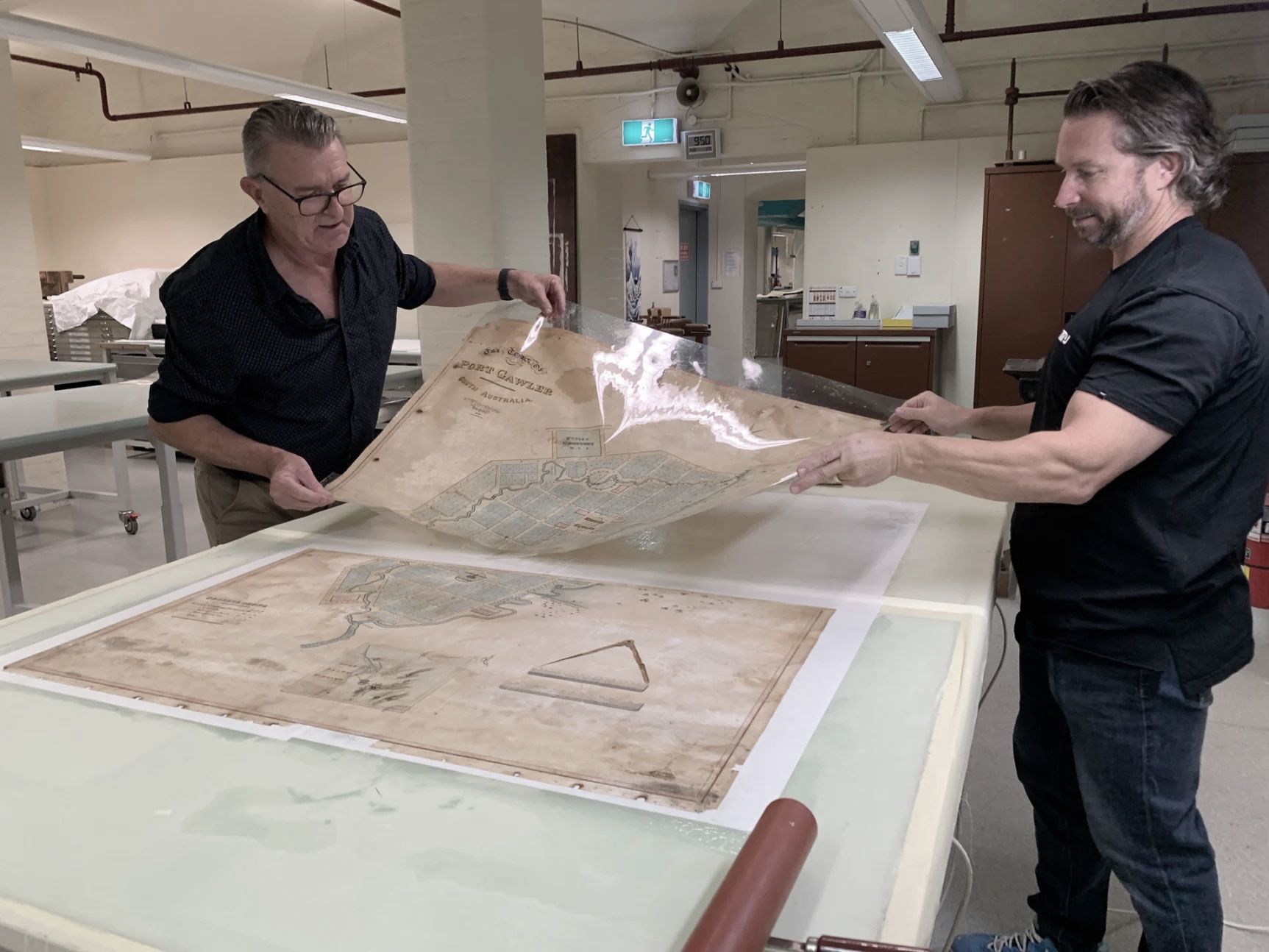 Peter Zajicek and Toby Woolley removing the map from the solution and attaching it to a new support lining which allowed parts of the image to be realigned.