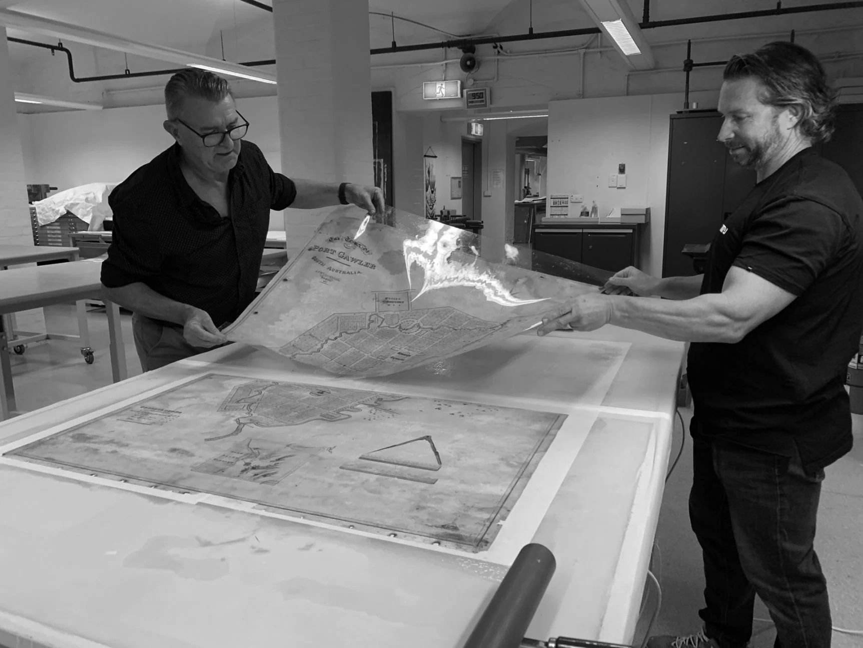 Peter Zajicek and Toby Woolley removing the map from the solution and attaching it to a new support lining which allowed parts of the image to be realigned.